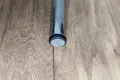 Angled top-down view of a round black LDPE injection-moulded foot insert fitted to the end of a metal tube leg, with a flat felted base profile visible.