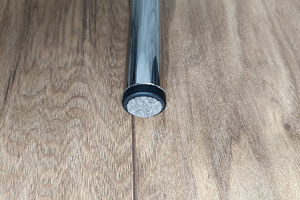 Angled top-down view of a round black LDPE injection-moulded foot insert fitted to the end of a metal tube leg, with a flat felted base profile visible.