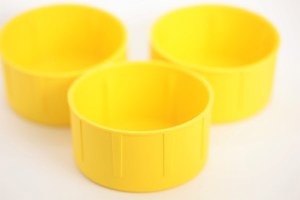 Close up of three yellow plastic scaffold protection caps showing internal ribs.
