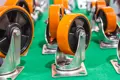 A number of castors with Plastic wheels and Orange tyres, with metal brackets. All upside down.