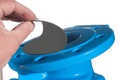 Black rubber protection disc being peeled away from painted blue flange surface.