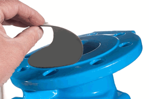 Black rubber protection disc being peeled away from painted blue flange surface.