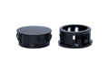 Two black plastic blanking plugs. Both standing up, showing opposite ends.