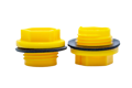 Two Yellow plastic BSP threaded plugs with rubber sealing washers. Both standing on opposite ends.