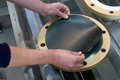 Round black rubber disc being fitted by hand to metal flange.