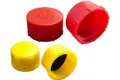 Angled view of four plastic threaded caps in red and yellow—two shown upright and two tilted to display internal threads and a sealing disc.