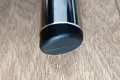 Angled top-down view of a round black LDPE injection-moulded foot insert fitted to the end of a metal tube leg, with an angled base profile visible.