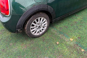 A car parked on top of plastic mesh that has been laid on grass.