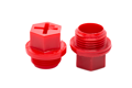Two red plastic BSP Threaded plugs with a hex shaped head and recessed cross.