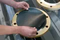 Self adhesive black rubber discs being glued onto metal flange plates.