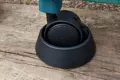 Angled view of a castor attached to a furniture leg, seated in a plastic castor cup designed to prevent movement.