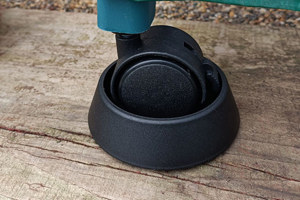 Angled view of a castor attached to a furniture leg, seated in a plastic castor cup designed to prevent movement.