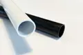 Two plastic extruded round tube profiles. One in white and one in black.