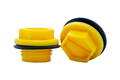 Two Yellow plastic metric threaded plugs with rubber sealing washers. One standing, one on its side.